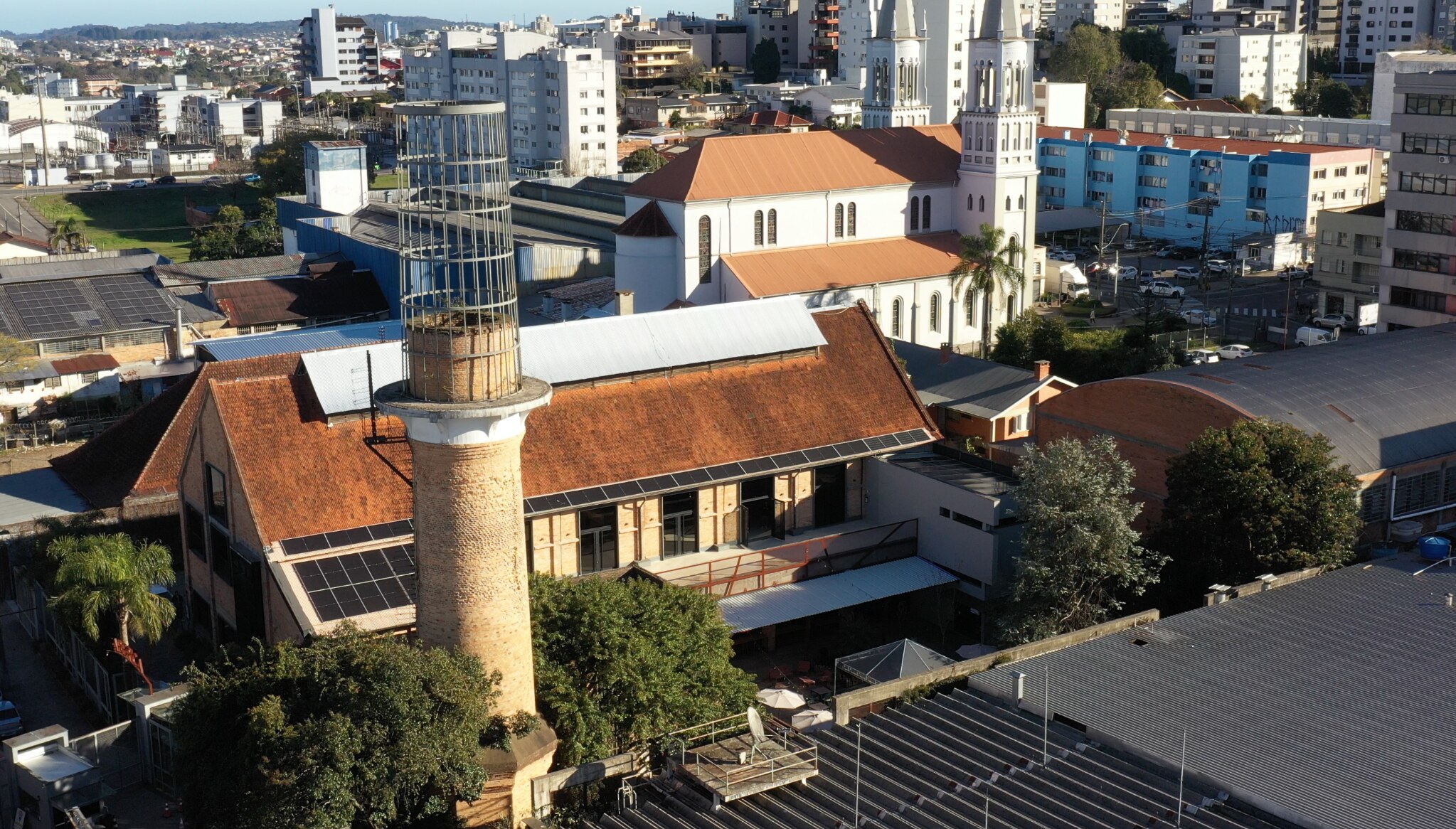 Vista aérea da sede da Treviso em edifício histórico de tijolos aparentes e antiga chaminé